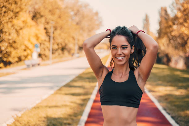 istock Fit female athlete tying hair before her workout outdoors on running track. 921777098