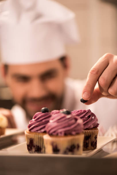 istock selective focus of confectioner decorating cupcakes with berries in restaurant kitchen 921780730