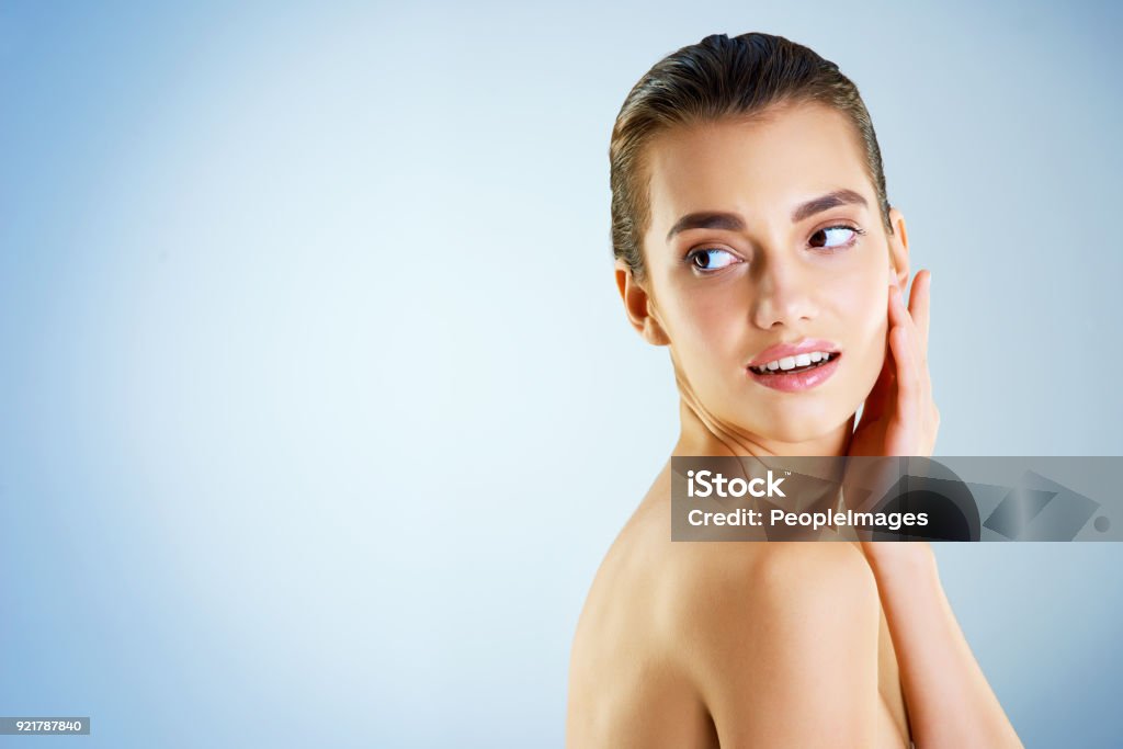 Every bit of her is beautiful Studio portrait of a beautiful young woman feeling her skin against a blue background 20-29 Years Stock Photo