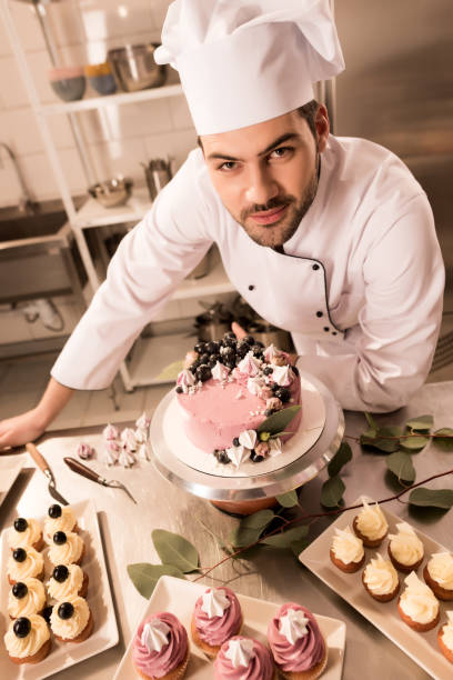 istock high angle view of confectioner standing near cake on counter in restaurant kitchen 921788708