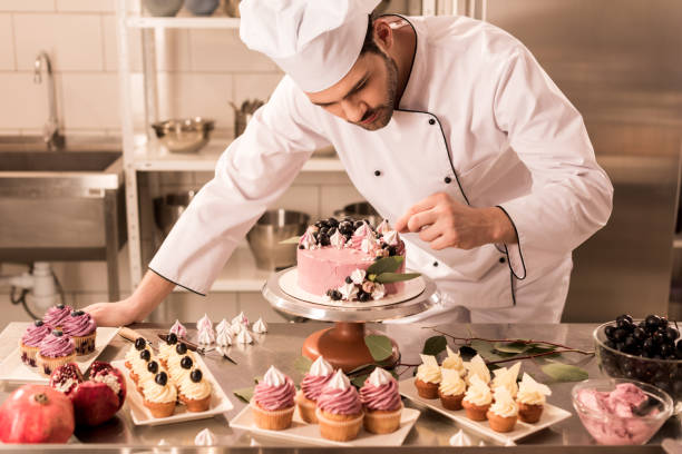 portrait of confectioner decorating cake in restaurant kitchen portrait of confectioner decorating cake in restaurant kitchen confectioner photos stock pictures, royalty-free photos & images