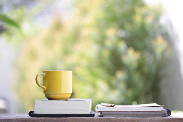 istock Yellow cup with notebooks on wooden table 921789060