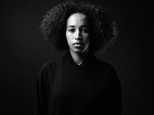 Black And White Studio Shot Of African Woman Against Black Background