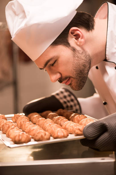 istock side view of confectioner looking at eclairs on baking pan in hands 921791990