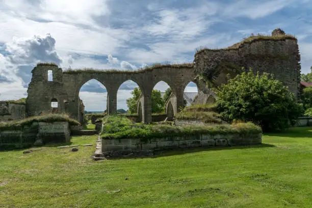 Ruin of a medieval monastery or cloister located in Alvastra, Sweden. On a beautiful sunny summer day with green grass and blue sky and some clouds