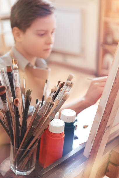 istock Serious teen boy painting masterpiece in studio 921803450