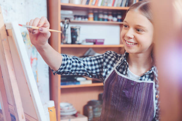 istock Radiant young lady smiling and painting 921803768