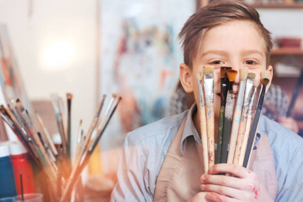 istock Adorable youngster hiding behind brushes for camera 921808670