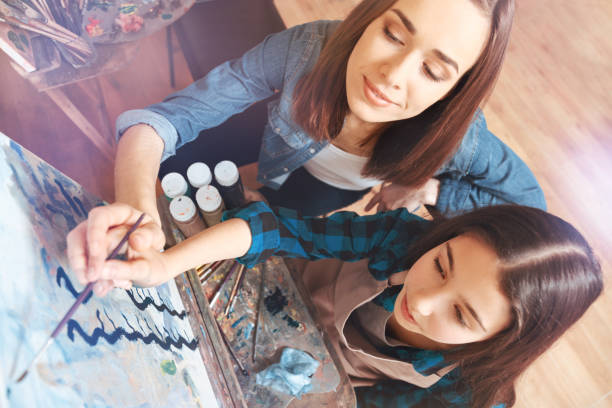 Female painter helping girl with painting