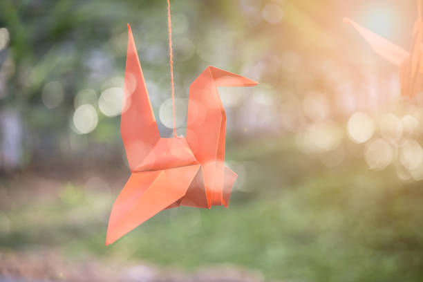 istock Orange paper bird is hung by a rope. 921812086