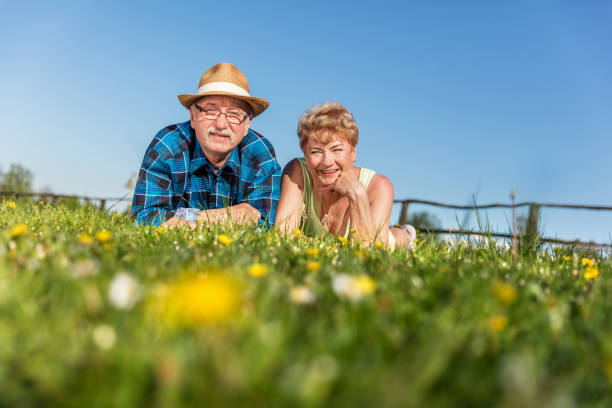 Retired couple lying on a blanket in a meadow, enjoying peaceful retirement together