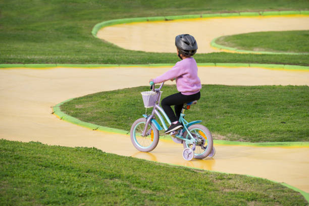 Cheerful boy with mouth open riding small bicycle while playing against white background