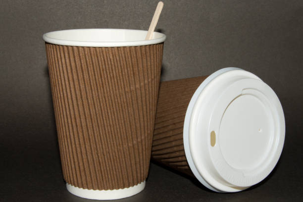 istock Two disposable cups for hot drinks on a dark backgrounds. Paper cups and white cap with the inscription Caution Contents Hot! 921825054