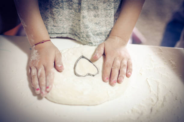 Hands of little girl making cookies. Close up.