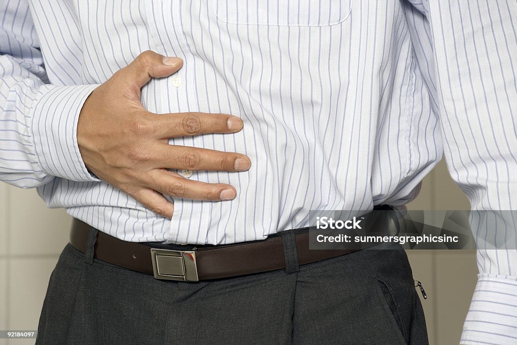 A man holding his hand to his stomach Closeup of a man having stomach pain or indigestion. Adult Stock Photo