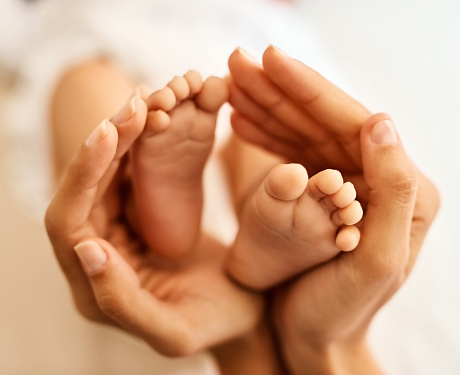 Cropped shot of a mother gently holding her baby’s feet
