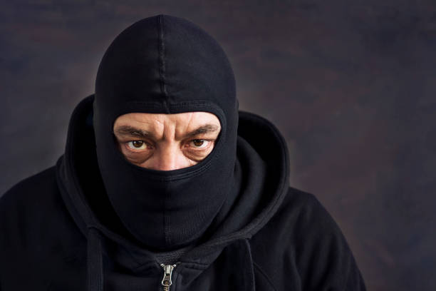 istock A man in a balaclava on a dark background. Copy space. Concept stealing, deception 921865600