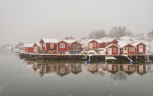 Snowing at the Swedish west coast. Idyllic red cottages in white winter landscape.