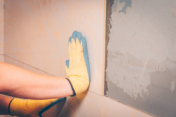 istock The working tiler mounts the tile on the wall, presses it with his hands 921869316