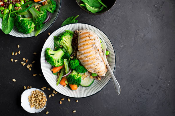 istock Grilled chicken breast, red rice and fresh broccoli vegetables, carrots, soybeans, spinach for garnish. With pine nuts. Top View 921869642