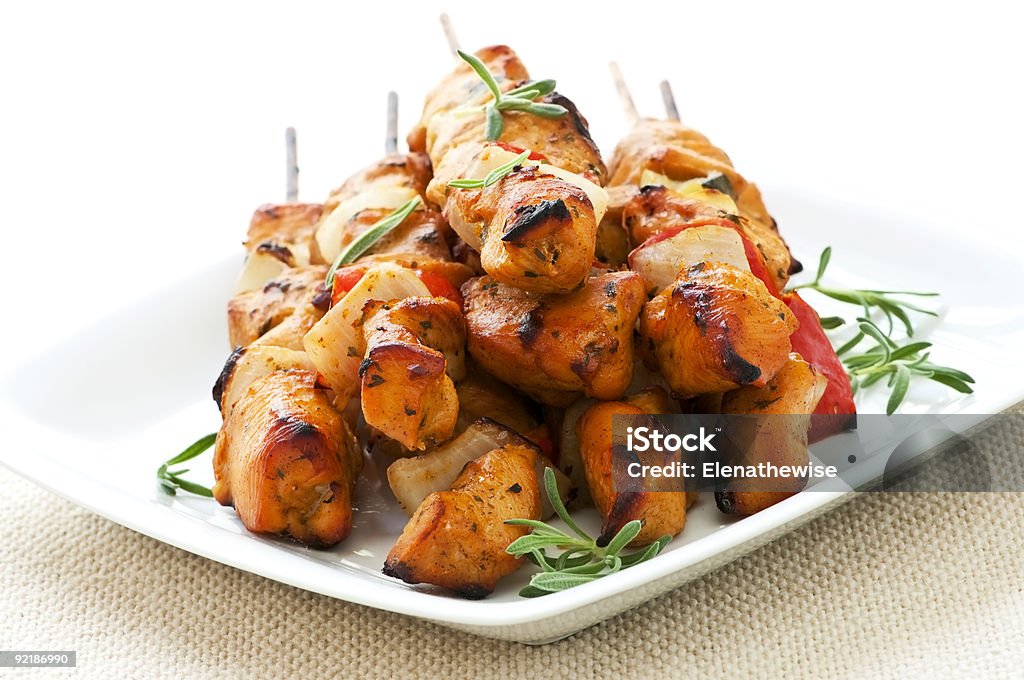 Chicken skewers on white plate with herbs Pile of barbecued chicken kebab appetizers on a plate Heap Stock Photo