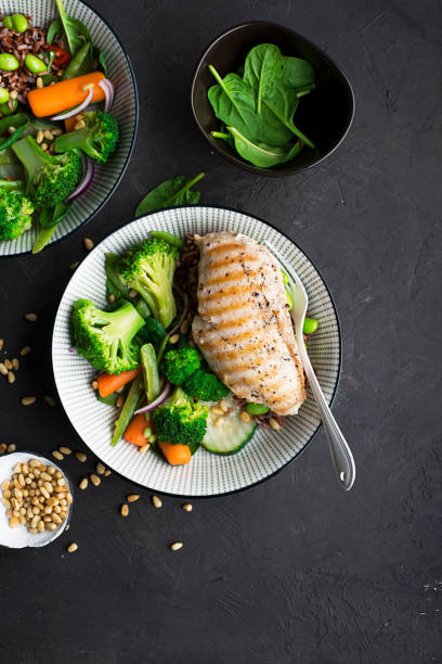 istock Grilled chicken breast, red rice and fresh broccoli vegetables, carrots, soybeans, spinach for garnish. With pine nuts. Top View 921870024