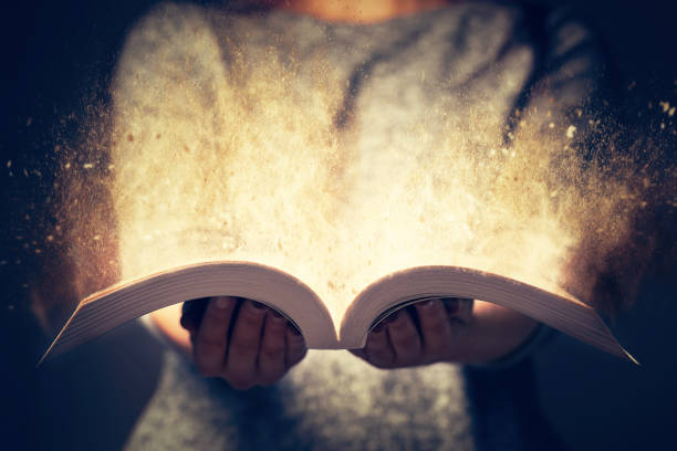 donna in possesso di un libro aperto pieno di luce. - narrare storie foto e immagini stock
