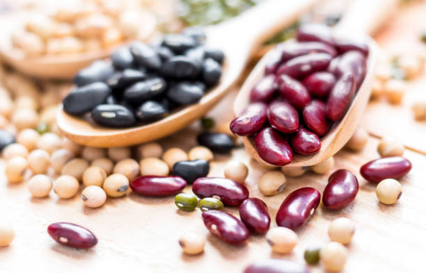 Many types of beans are separated in a spoon on a wood table such as mung bean, soybean, black bean, red bean. selective focus. Many types of beans are separated in a spoon on a wood table such as mung bean, soybean, black bean, red bean. selective focus. red mung bean stock pictures, royalty-free photos & images