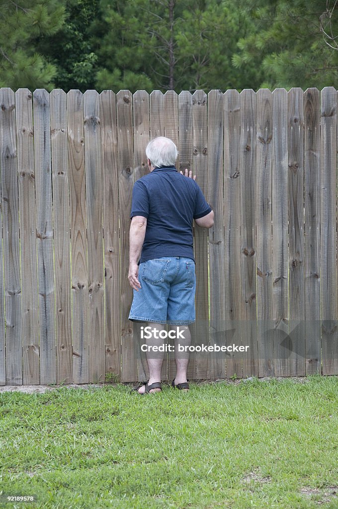 Hombre adulto echar un vistazo a través de un orificio en la valla - Foto de stock de Mirilla libre de derechos