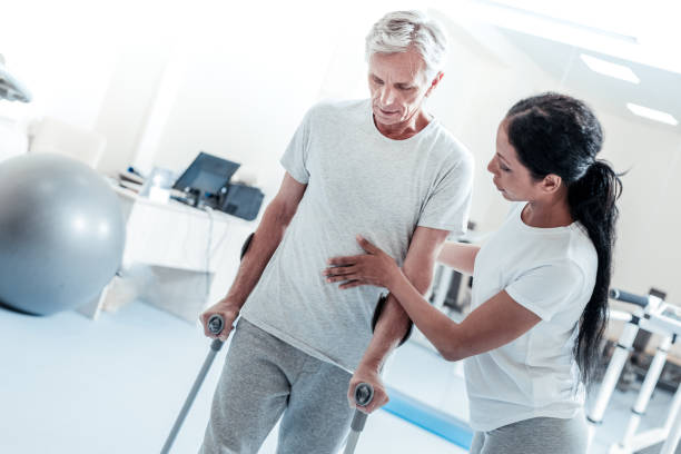 istock Determined woman helping old man stand 921899584