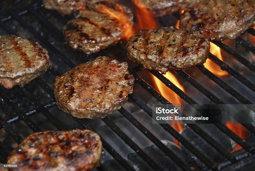 Hamburgers on barbeque Hamburgers cooking on barbeque grill with flames Barbecue - Meal Stock Photo