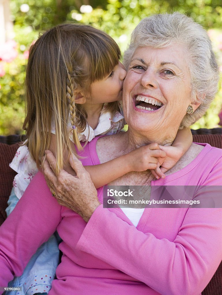 Grandmother getting a kiss from granddaughter Grandmother getting a kiss from granddaughter ingarden Kissing Stock Photo