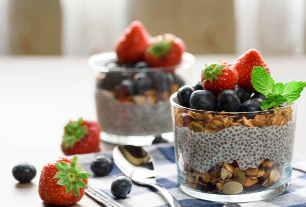 Yogurt with granola, fresh blueberries, chia seeds and oats in a glass over wood background. close up