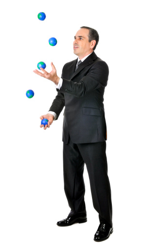 Business man in suit juggling planet earth balls