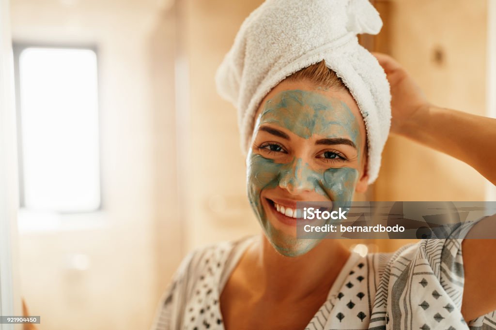 Rejuvenating her skin Portrait of an attractive young woman standing in the bathroom with a facial mask Facial Mask - Beauty Product Stock Photo