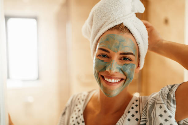 Rejuvenating her skin Portrait of an attractive young woman standing in the bathroom with a facial mask green clay stock pictures, royalty-free photos & images