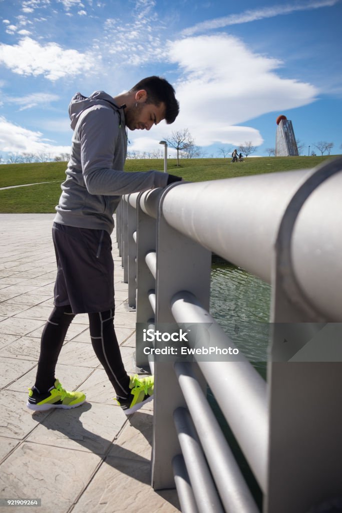 Young athletic man is preparing before running in a city park in winter. One young caucasian athletic man is preparing before running in a city park in winter. Active Lifestyle Stock Photo