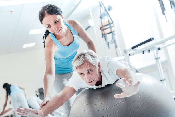 istock Cheerful female trainer helping disabled man train 921910636