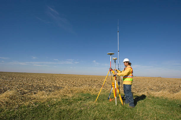 A land surveyor stood in a field taking readings with GPS stock photo
