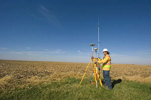 Photo of A land surveyor stood in a field taking readings with GPS