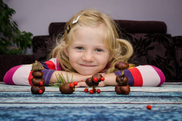 child making chestnut figures from autumn chestnuts stock photo