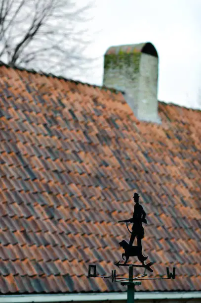Windvane with hunter and dog opposite the traditional tile roof somewhere in Holland