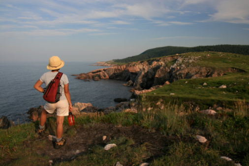 Rear view of a two women walking along a narrow pathway on cliff