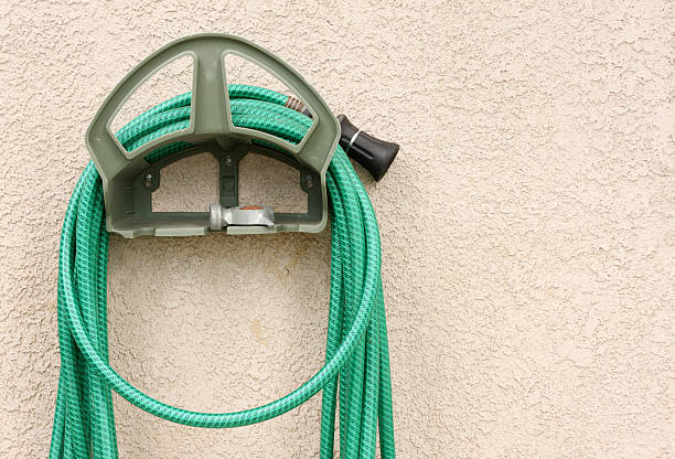 Garden Hose Hanging on Stucco Wall  garden hose stock pictures, royalty-free photos & images