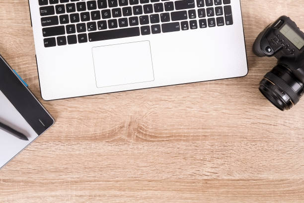 istock Photo blogger / photographer / it specialist's typical office space table with laptop, blank screen, coffee cup and electronics. Top view, copy space, flat lay, overhead, backdrop. 921937700