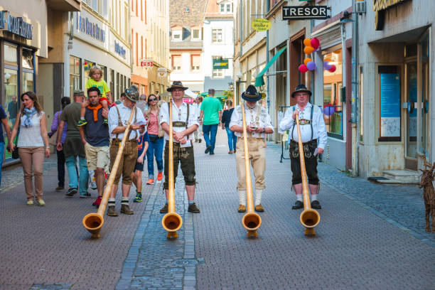 Alphorn player in traditional Bavarian costumes performing on the street of Heidelberg at the fall folk festival. Heidelberg, Germany - September 24 2016. Heidelberg, Germany - September 24, 2016: Alphorn player in traditional Bavarian costumes performing on the street of Heidelberg at the fall folk festival. alpenhorn stock pictures, royalty-free photos & images