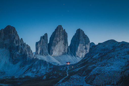 Beautiful view of famous Tre Cime di Lavaredo mountains in the Dolomites mountain range with famous Rifugio Antonio Locatelli alpine hut on a clear starry night in summer, South Tyrol, Italy