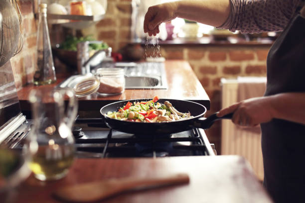 Cooking vegetables, step seven, seasoning Cooking vegetables in real, rustic kitchen. Natural light, short DOF, a little bit noisy. cooking pan photos stock pictures, royalty-free photos & images