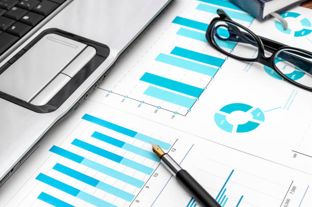istock Financial graphs with laptop, eyeglasses, pen and notepad on the workplace. 921964766