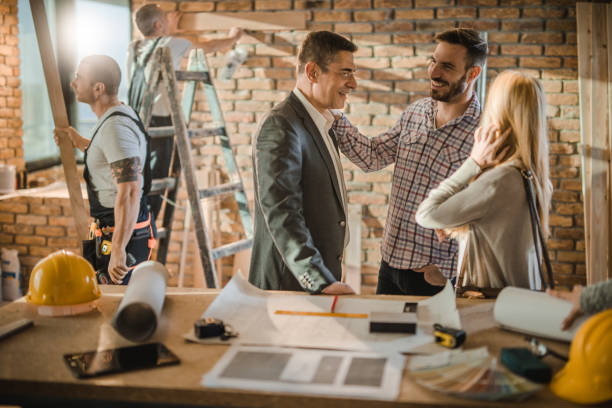 istock Mid adult building contractor communicating with happy couple at construction site. 921964874